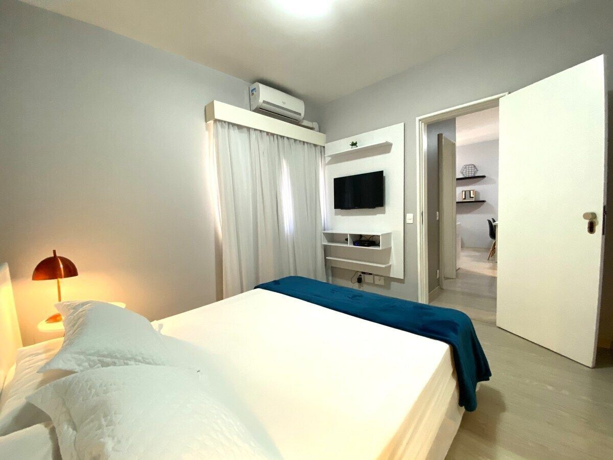 Une chambre d’hôtel avec un lit, un téléviseur fixé au mur et une porte donnant sur une autre pièce.