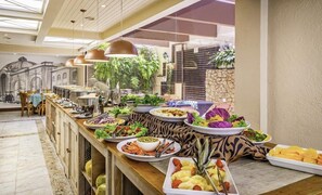 Un buffet proposant une variété de plats, un long comptoir et une vue sur un bâtiment orné d’arcades.