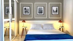 A bedroom with a bed, two bedside tables, a mirror, and framed pictures on the wall. - FLAT em LOCALIZAÇÃO FANTÁSTICA (São Paulo)