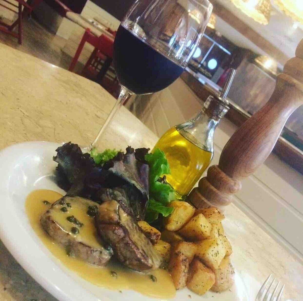 A plate with meat, potatoes, and a glass of red wine.