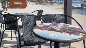 An outdoor seating area with wicker chairs and a round table, overlooking a beach and marina. - Gemütliches Appartement, 25 qm in Biograd na Moru (Biograd na Moru)