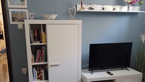 A living room with a bookshelf, a flat-screen TV, a patterned table, and a chair. - Gemütliches Appartement, 25 qm in Biograd na Moru (Biograd na Moru)