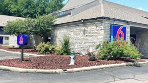 A stone building with a '6' sign, indicating a motel or similar lodging. - Studio 6 Suites Dayton, Oh - Englewood (Englewood)