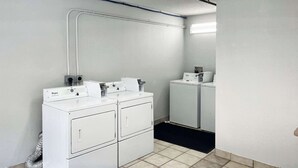 A laundry room with stacked washers and dryers, a visible vent, and a ceiling-mounted fire alarm. - Studio 6 Suites Dayton, Oh - Englewood (Englewood)