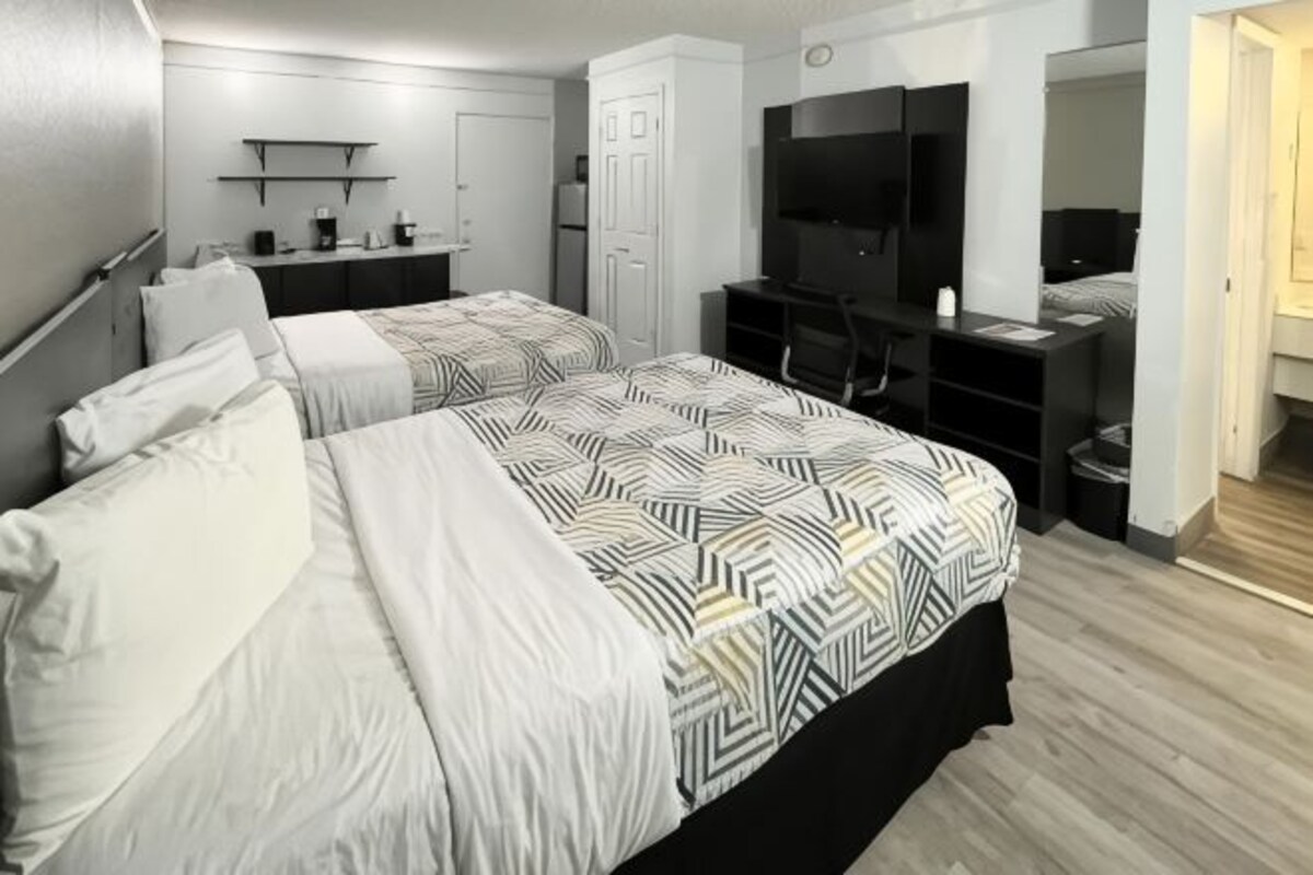 A hotel room with two beds, a desk, a TV, and a wardrobe.