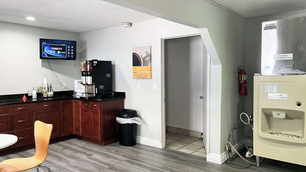 A modern kitchen with a coffee machine, a TV mounted on the wall, and a refrigerator. - Studio 6 Suites Dayton, Oh - Englewood (Englewood)