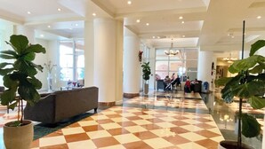 A spacious lobby with a checkered floor, large potted plants, a sofa, and a reception area in the background. - The Javiera Beach Condo! 3BR/2BA in Sunny Isles Beach (Sunny Isles Beach)