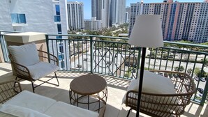 A balcony with wicker furniture, a table, and a lamp. - The Javiera Beach Condo! 3BR/2BA in Sunny Isles Beach (Sunny Isles Beach)