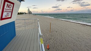 A beach with a lifeguard sign, a blue building, and a clear sky. - The Javiera Beach Condo! 3BR/2BA in Sunny Isles Beach (Sunny Isles Beach)