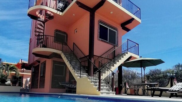 A multi-story hotel with a pool, featuring balconies, a staircase, and outdoor seating. - Apartamento #1-1 Casalaspalmas Puntademita (Punta de Mita)