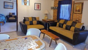 A living room with two sofas, a coffee table, and a TV. There is a ceiling fan, a lamp, and a picture frame on the wall. - Apartamento #1-1 Casalaspalmas Puntademita (Punta de Mita)