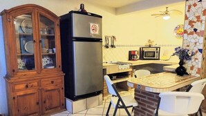 A kitchen with a refrigerator, microwave, stove, and a dining area with chairs. - Apartamento #1-1 Casalaspalmas Puntademita (Punta de Mita)