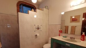 A bathroom with a shower, toilet, sink, and a mirror with a decorative picture. - 2 BdD Villa Completa Casalaspalmas-punta De Mita (Punta de Mita)