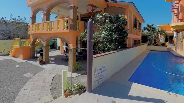 A building with a swimming pool, outdoor seating, and a sign in Spanish. - 2 BdD Villa Completa Casalaspalmas-punta De Mita (Punta de Mita)