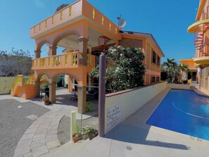 Un edificio con piscina, zona de estar al aire libre y un cartel en español.
