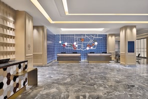 Experience the sophisticated lobby with a sleek reception desk, unique art installation, and polished floor.