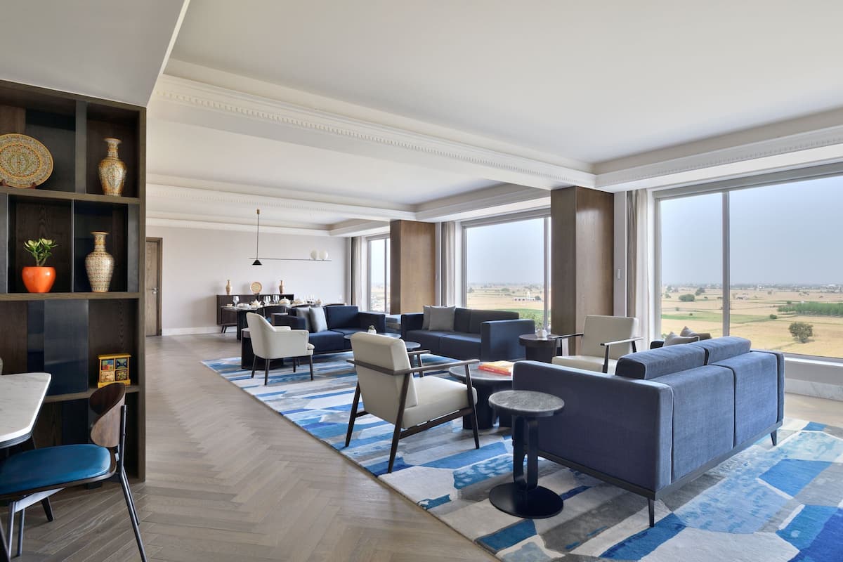 A spacious living area with a large sofa set, a dining table, and a bookshelf.