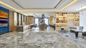 A spacious lobby with a marble floor, a reception desk, a seating area with sofas, and a decorative sculpture. - Le Méridien Amritsar (Amritsar)