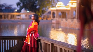 A person in traditional attire standing by a water feature with illuminated structures in the background. - Le Méridien Amritsar (Amritsar)
