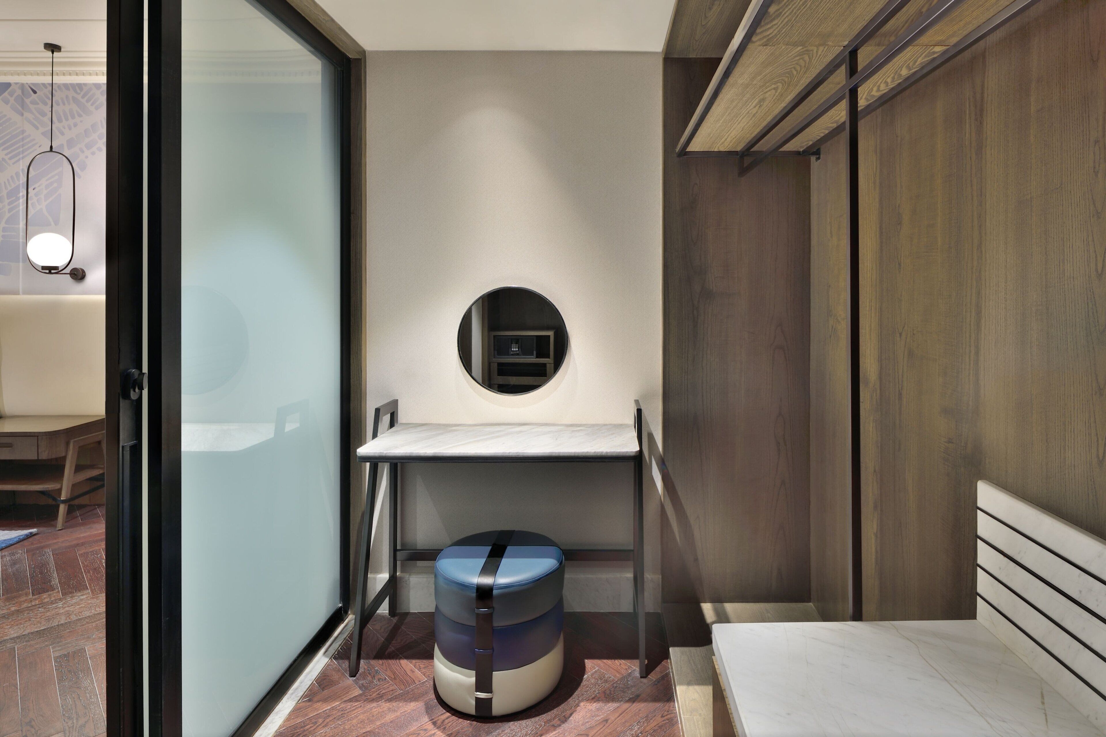A compact bedroom with a bed, a small round table, and a stool.