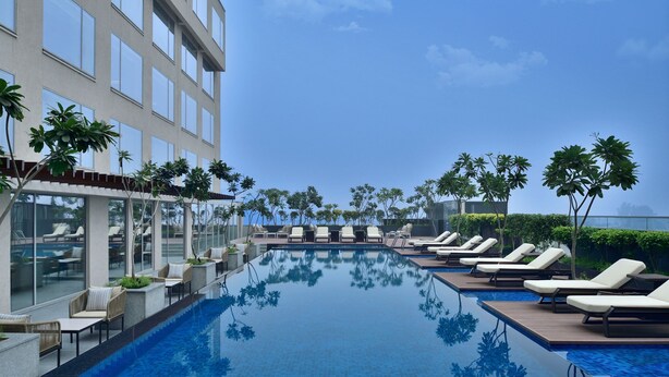 A modern hotel pool area with lounge chairs and a clear blue pool. - Le Méridien Amritsar (Amritsar)