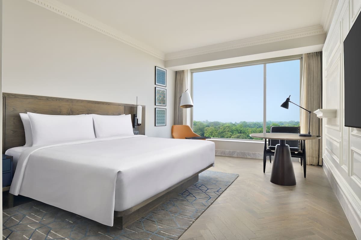 A hotel room with a large bed, a desk, and a view of the outdoors.