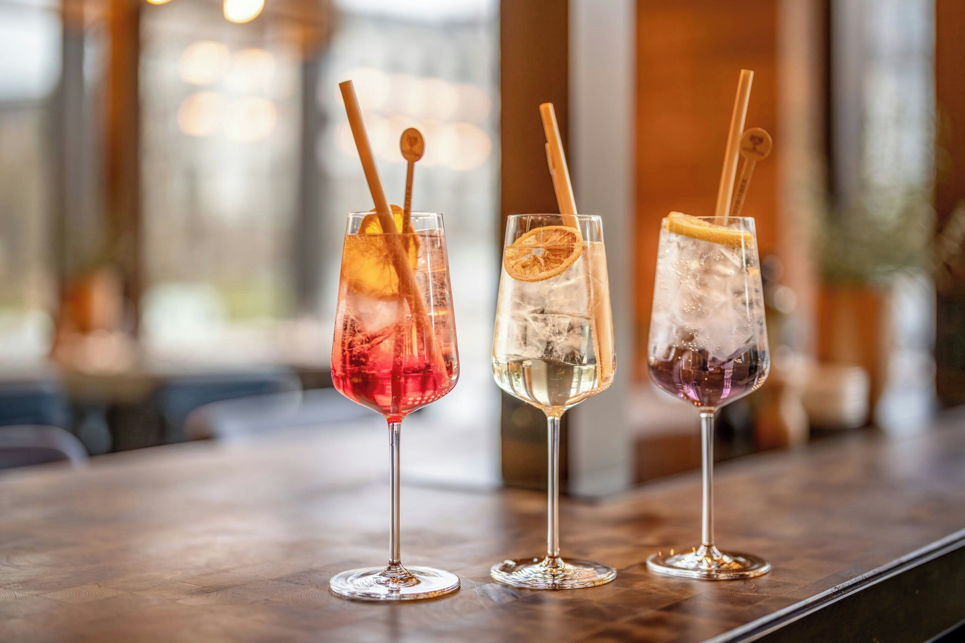 Tres vasos de bebidas sobre una barra.