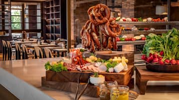 A buffet with various cheeses, meats, and vegetables.