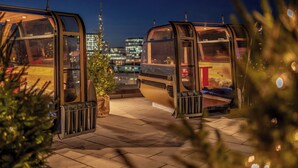 Dos cabañas con paredes de vidrio y una vista panorámica del paisaje urbano.