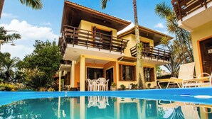 A two-story house with a balcony, a swimming pool, and palm trees. - Bollté Praia Boutique Pousada - Campeche - SC (Florianópolis)