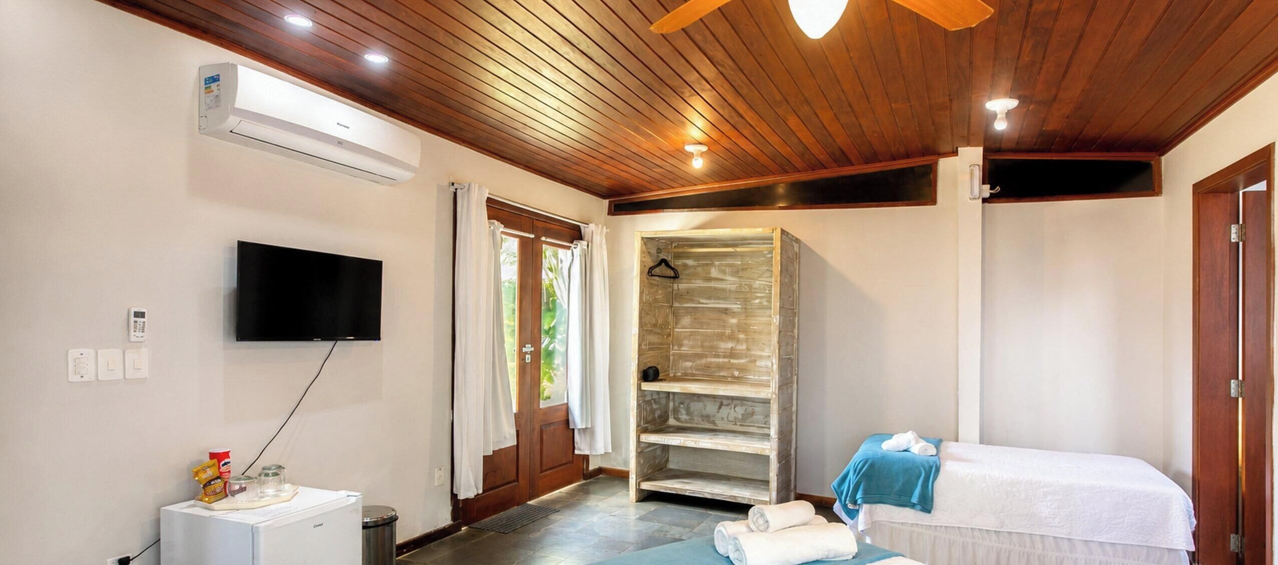 Une chambre à coucher avec un lit, une télévision, un climatiseur, une douche et un plafond en bois.