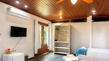 A bedroom with a bed, a TV, an air conditioner, a shower, and a wooden ceiling.