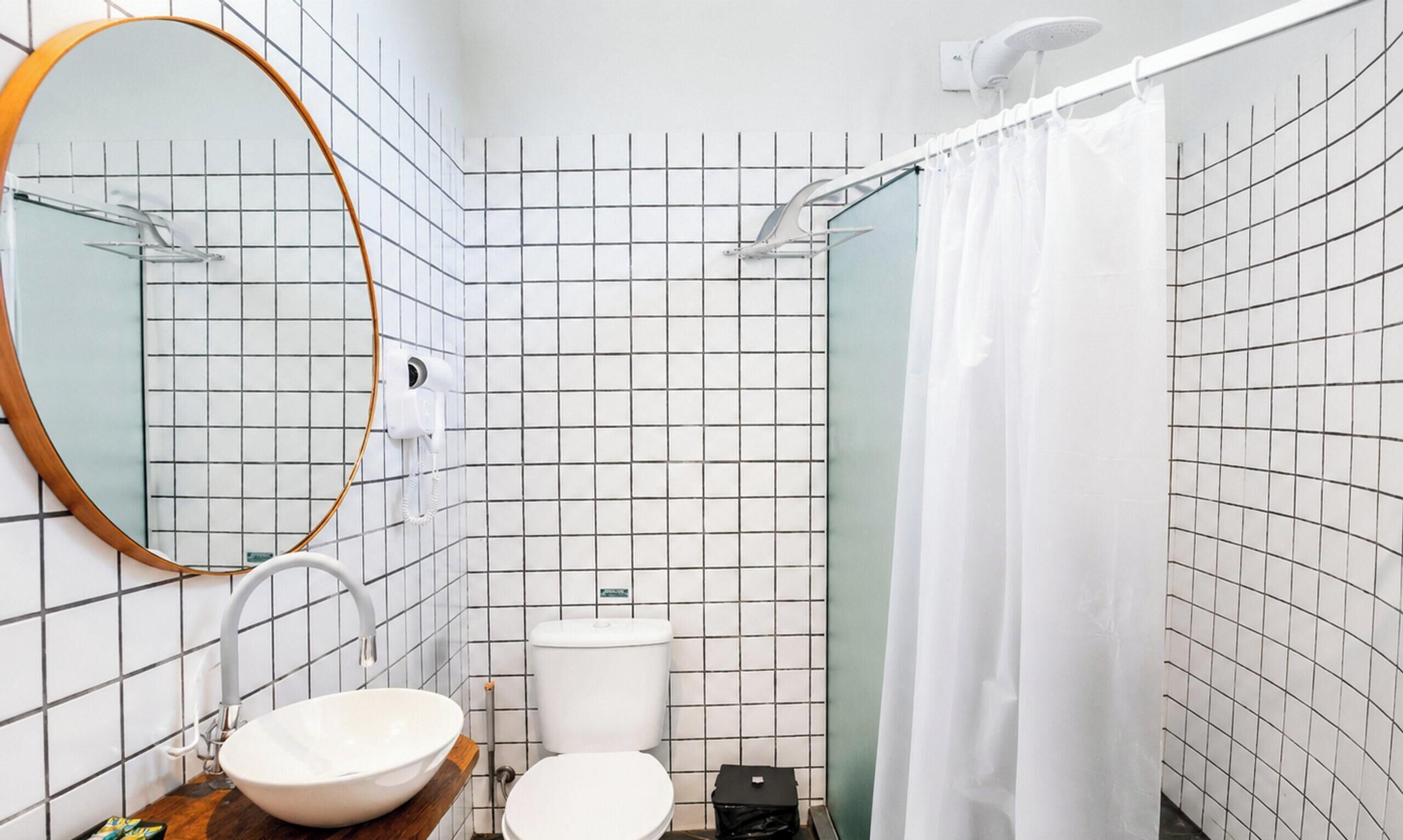 Un baño con lavamanos blanco, inodoro y cortina de ducha.