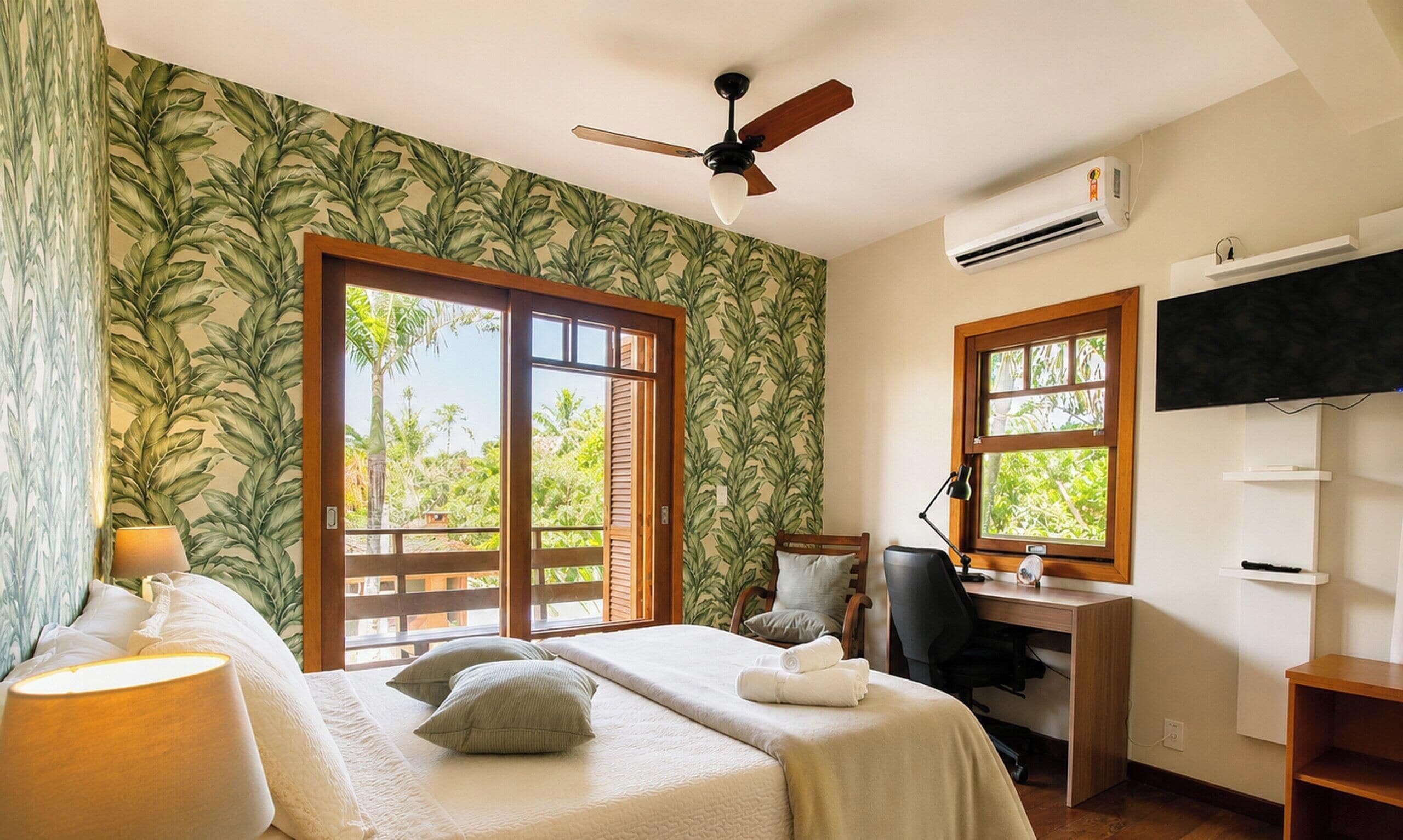 A bedroom with a bed, a desk, a chair, a TV, and a ceiling fan.