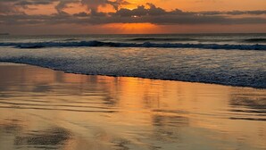 Une plage avec des vagues et un coucher de soleil.