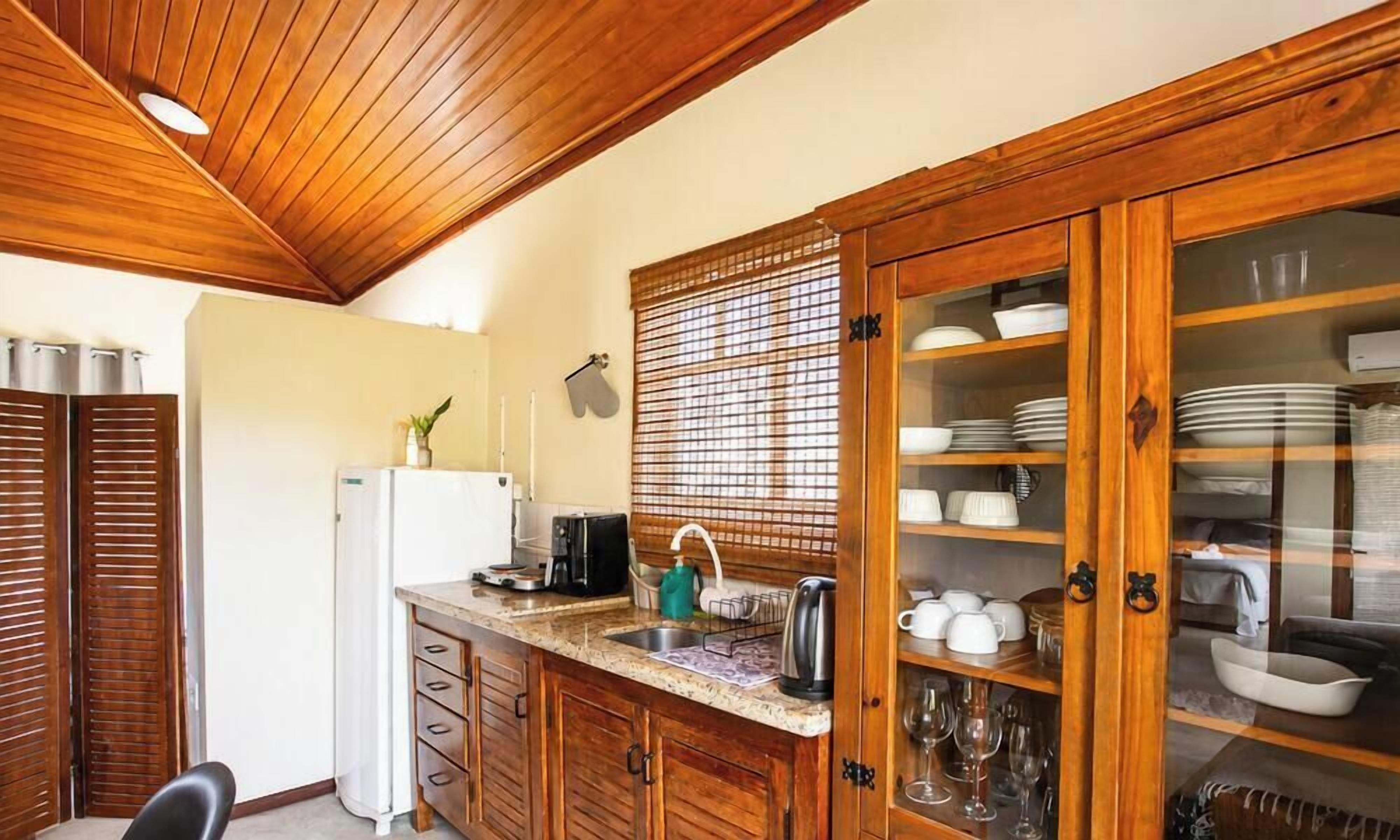 Una cocina con armarios de madera, un lavabo y una encimera con diversos utensilios de cocina.