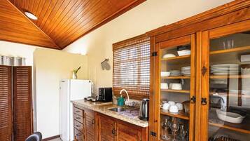 Una cocina con armarios de madera, un lavabo y una encimera con diversos utensilios de cocina.