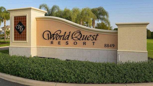 A sign for World Quest Resort with a large, curved entrance and a contact number.