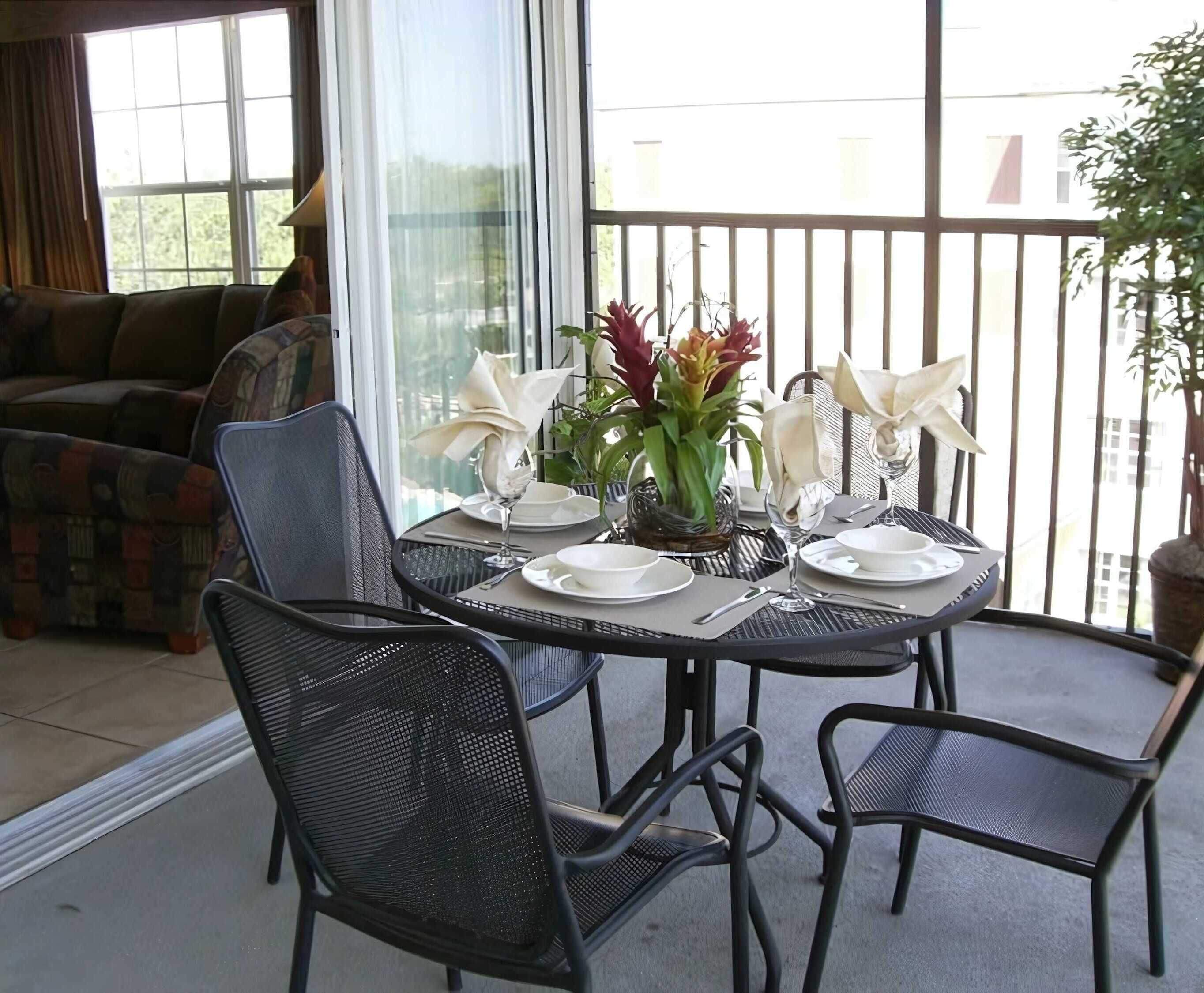 A dining area with a round table set for four, surrounded by black mesh chairs.