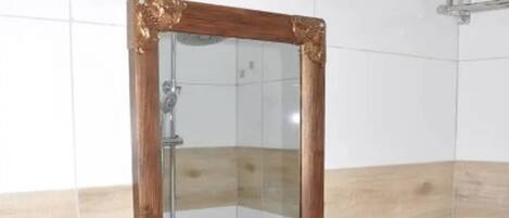Un baño con un lavamanos blanco, un espejo con marco de madera y un perchero para toallas.
