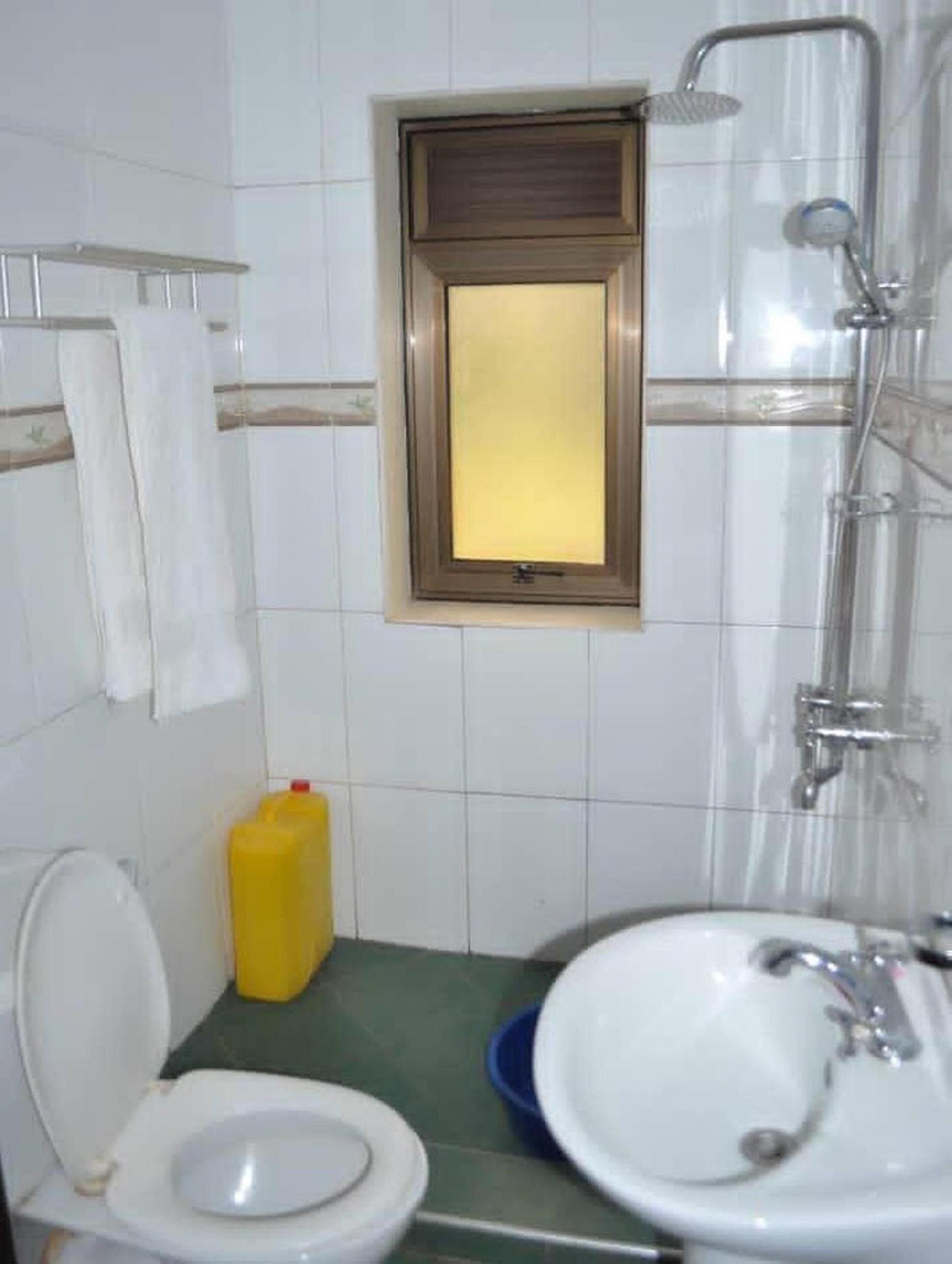Un baño con inodoro, lavamanos, ducha y una pequeña ventana.