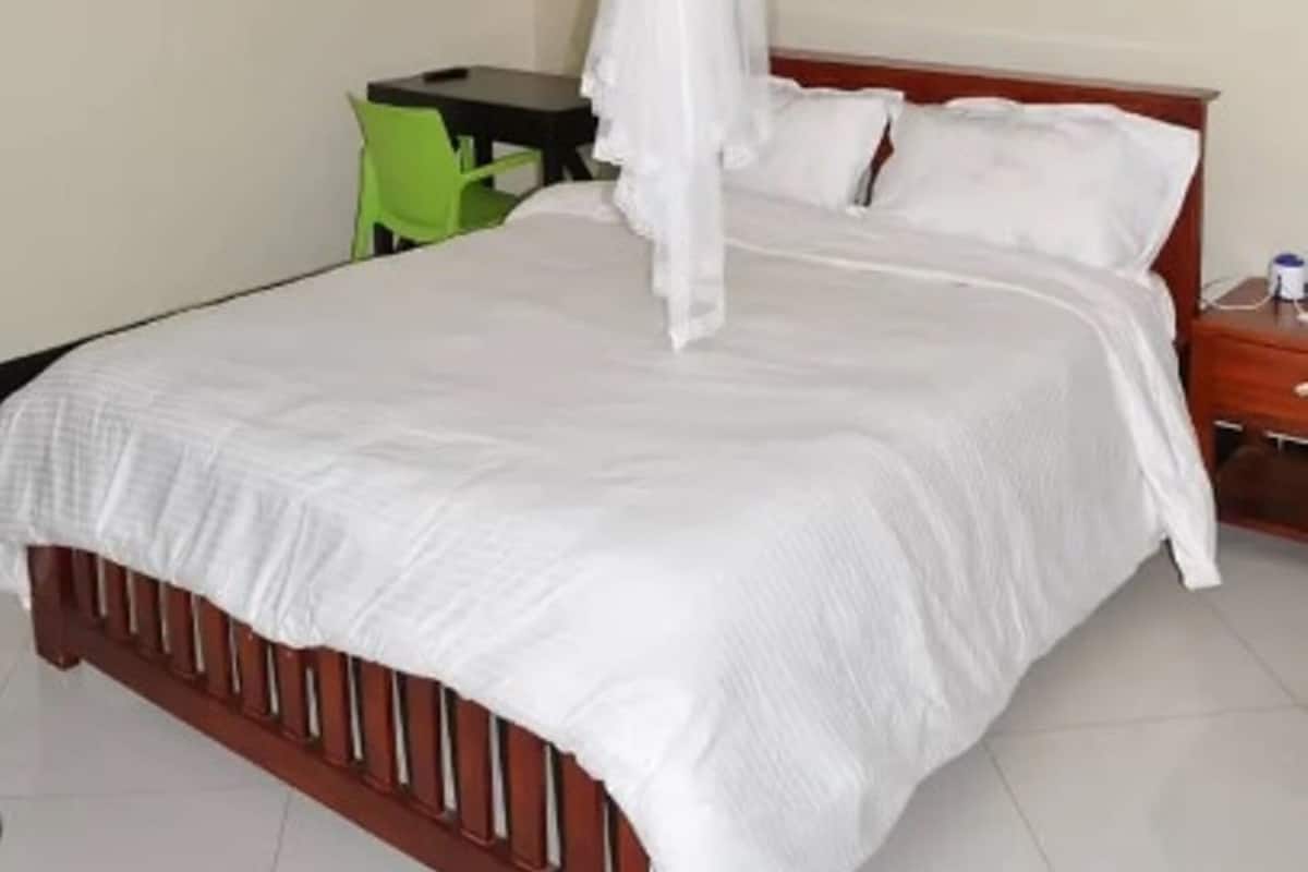 Un dormitorio con cama, una silla verde, una mesita y una mesita de noche.