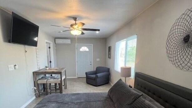 A bedroom with a bed, a desk, a chair, a ceiling fan, and a TV mounted on the wall. - Executive Suite #2 with Parking (Pima County)