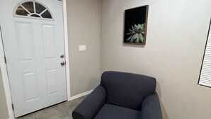 A room with a door, a framed picture on the wall, and a dark-colored armchair. - Executive Suite #2 with Parking (Pima County)