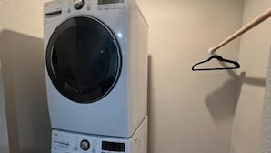 A stacked washer and dryer in a corner with a towel rack on the wall. - Executive Suite #2 with Parking (Pima County)