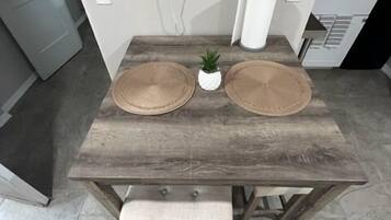 Une table à manger avec deux sets de table ronds, une petite plante en pot et un banc.
