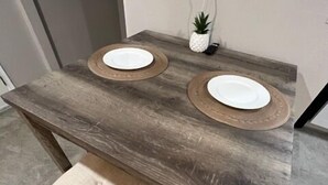 A wooden dining table with two white plates and a small potted plant. - NW Executive 1BR with Laundry and Parking (Casas Adobes)