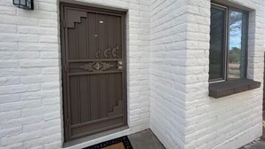 A white brick building with a dark brown door featuring decorative elements and a number '3'. - NW Executive 1BR with Laundry and Parking (Casas Adobes)
