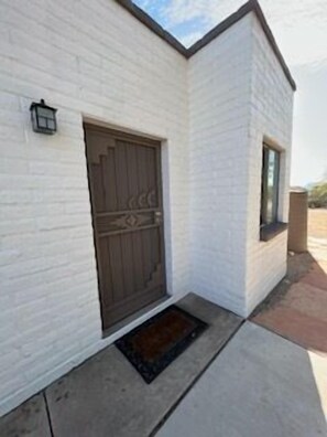 Um edifício branco com uma porta marrom escura e uma pequena janela.