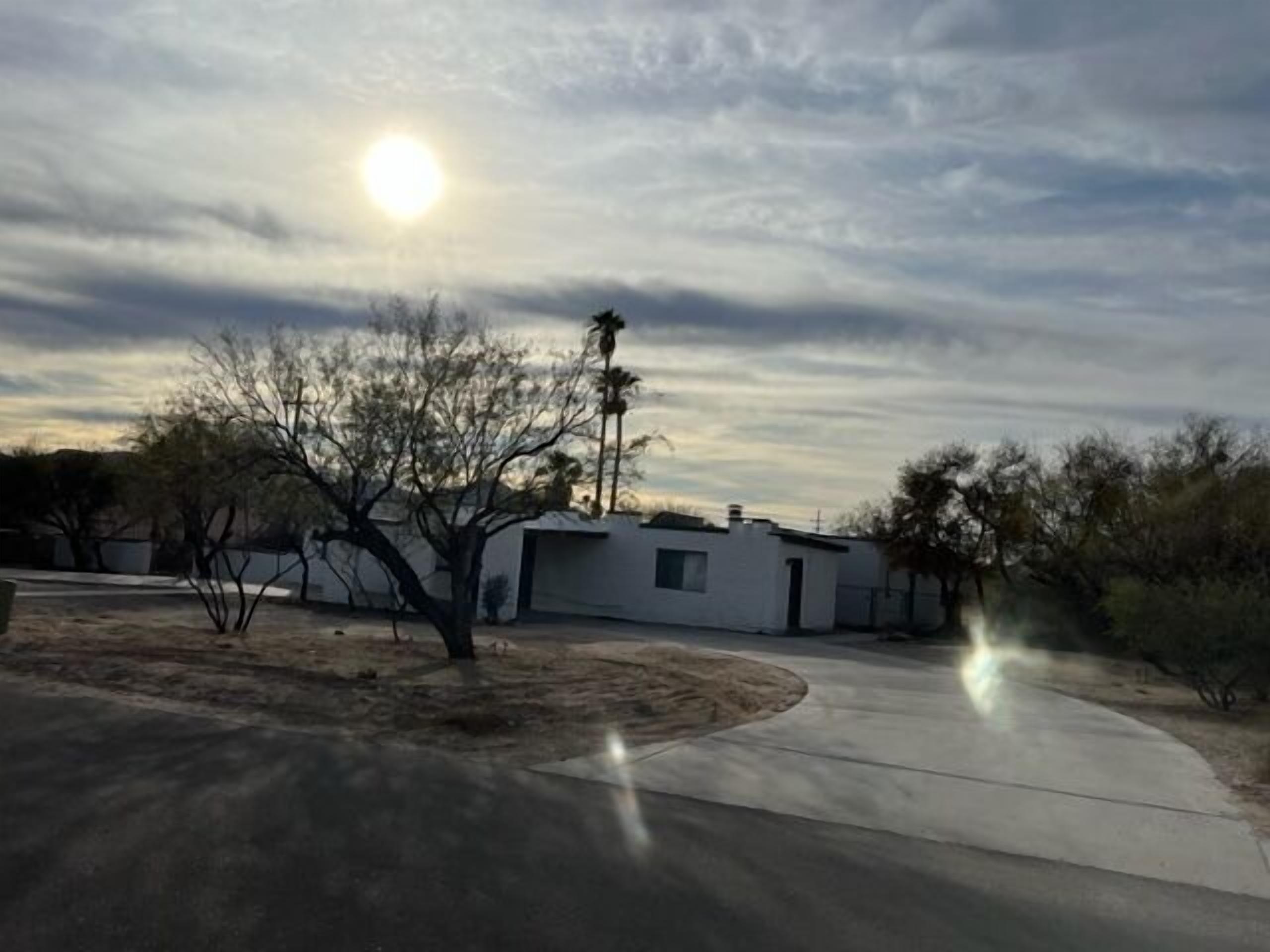 A residential area with a house, a tree, and a clear sky.